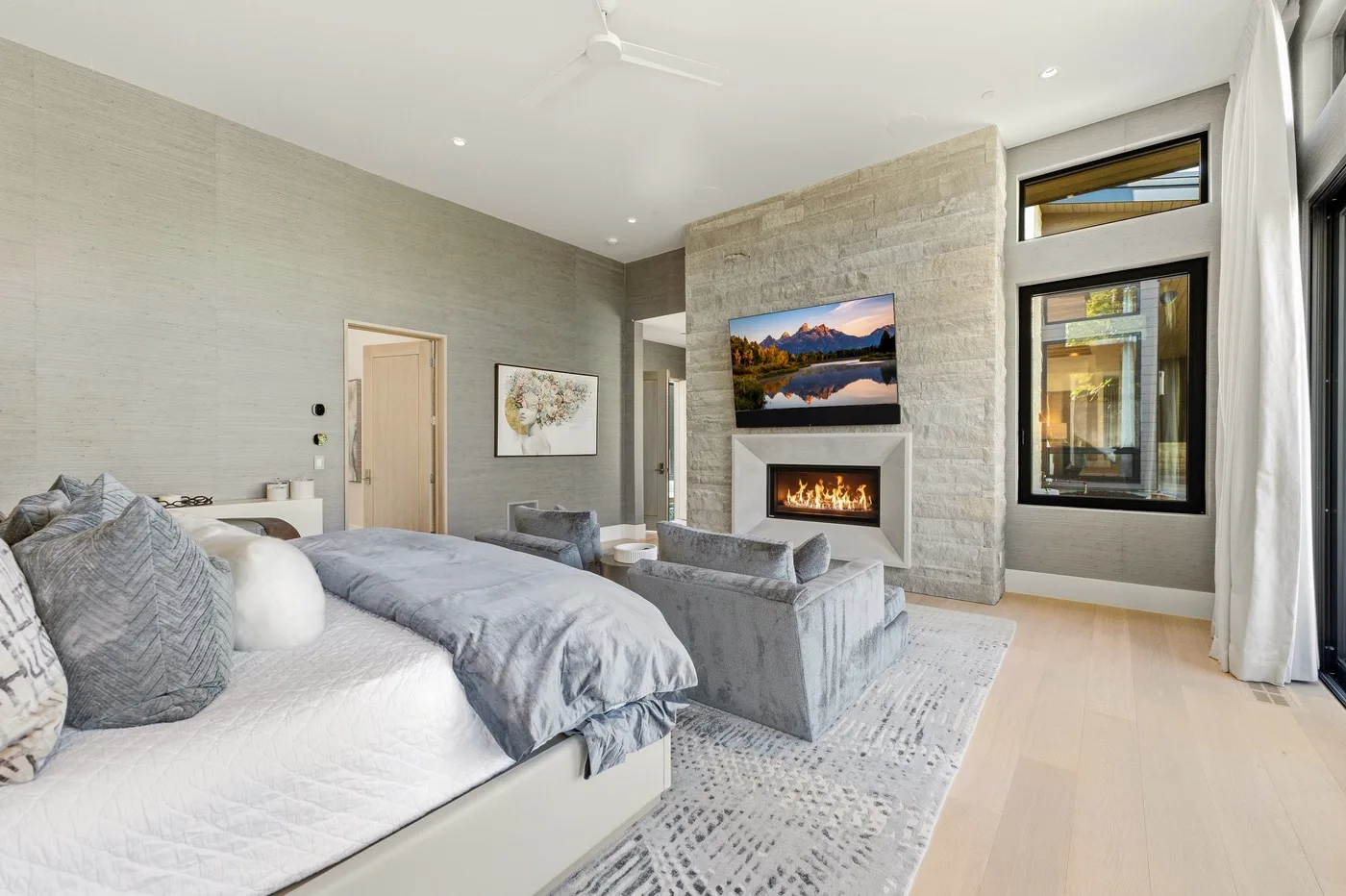 A spacious bedroom with a bed, seating area, and fireplace.