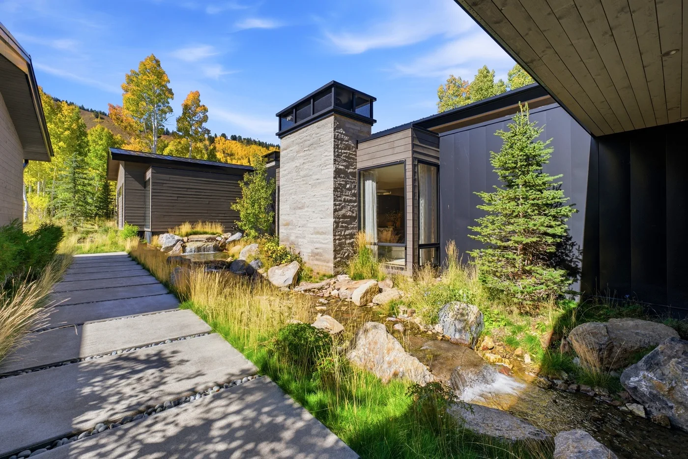 A modern house exterior with a paved path and landscaped garden.