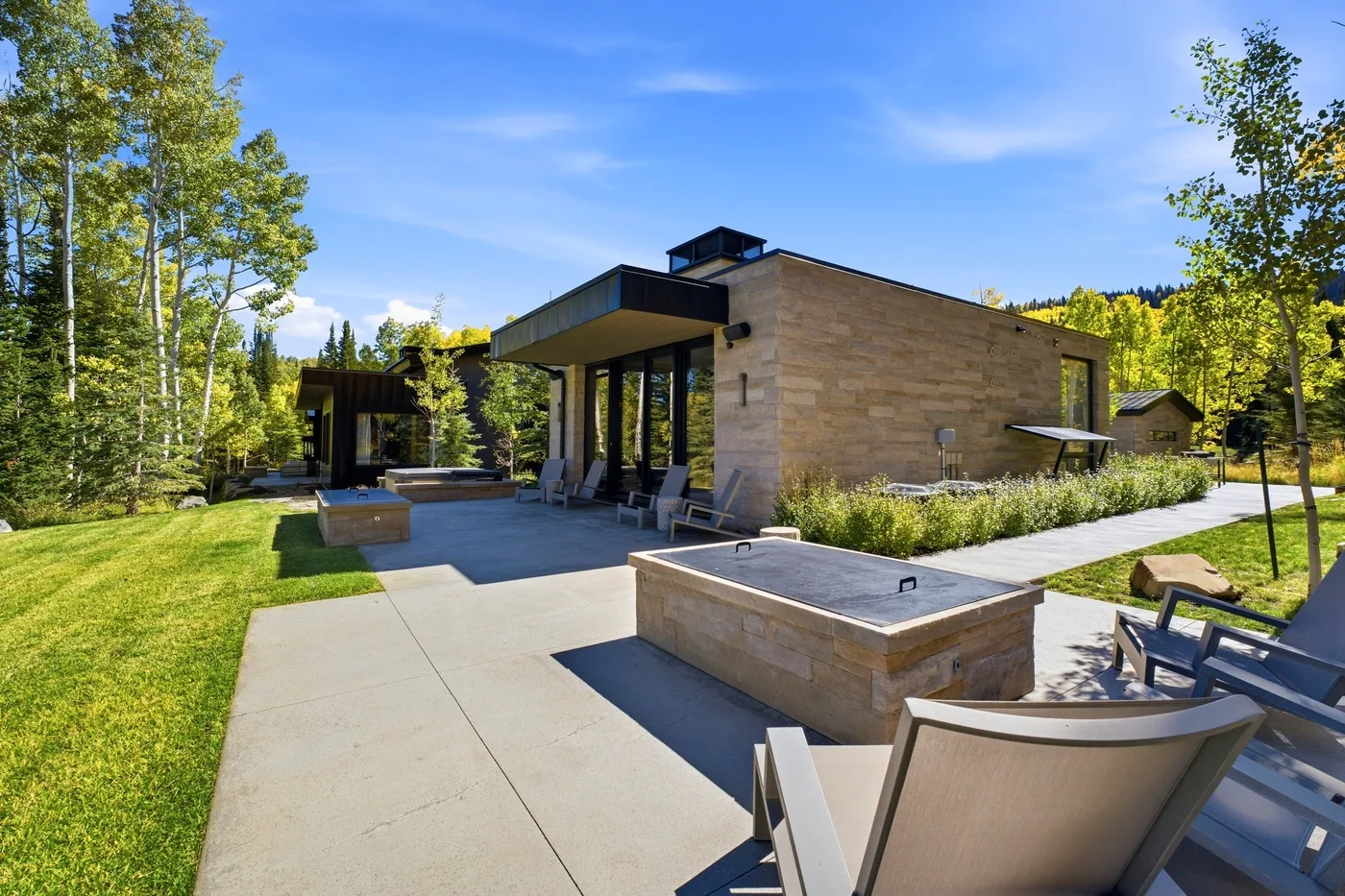 A modern outdoor patio with a built-in rectangular water feature and surrounding greenery.