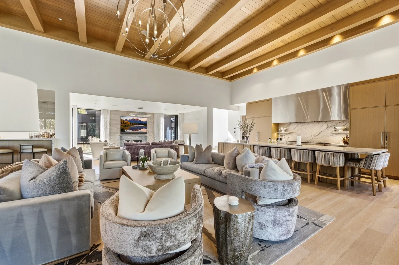 An open-plan living room and kitchen with seating beneath a wood-beamed ceiling.