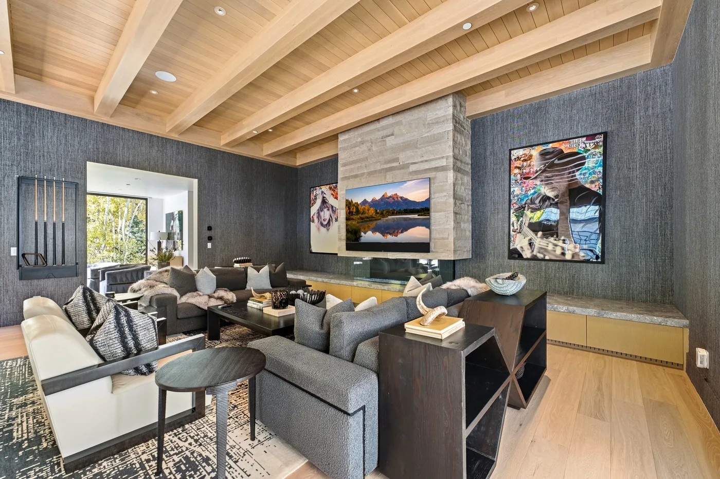 A living room with seating arranged around a low table beneath a wood-beamed ceiling.