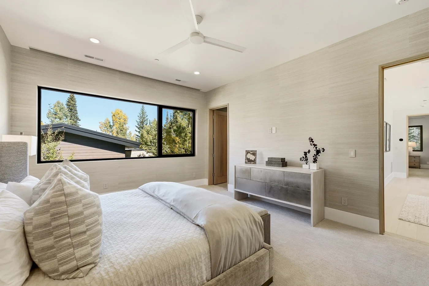 A bright bedroom with a large window and a low dresser.