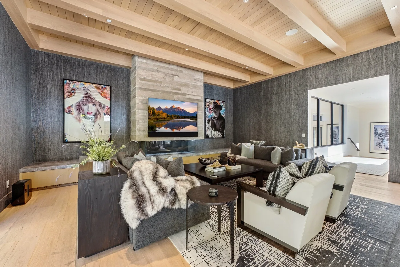 A living room with seating arranged around a coffee table beneath a wood-beam ceiling.