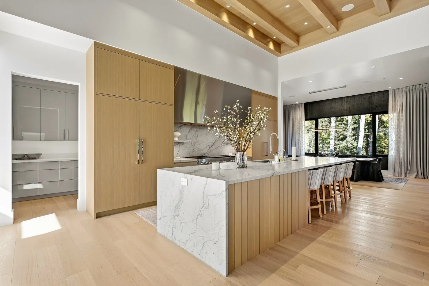 A modern kitchen with a large island and a dining area by the windows.