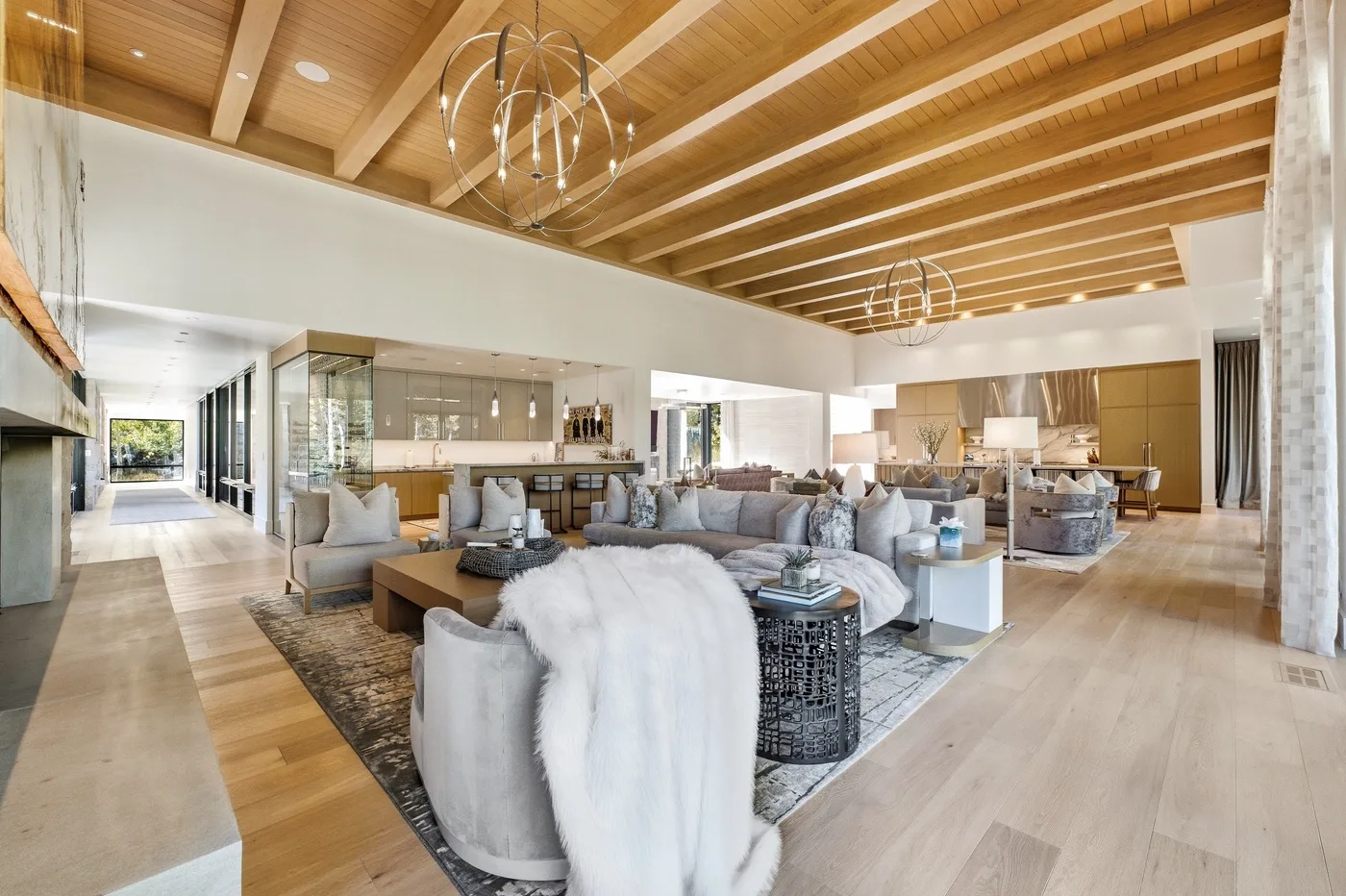 A spacious open-plan living area with seating beneath a wood-beamed ceiling.