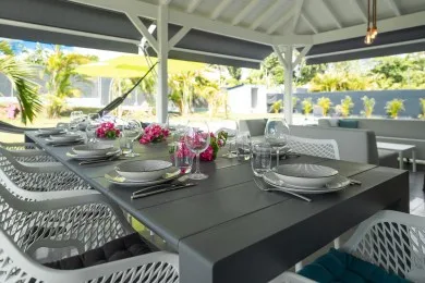 A covered outdoor dining area with a set table and surrounding seating.