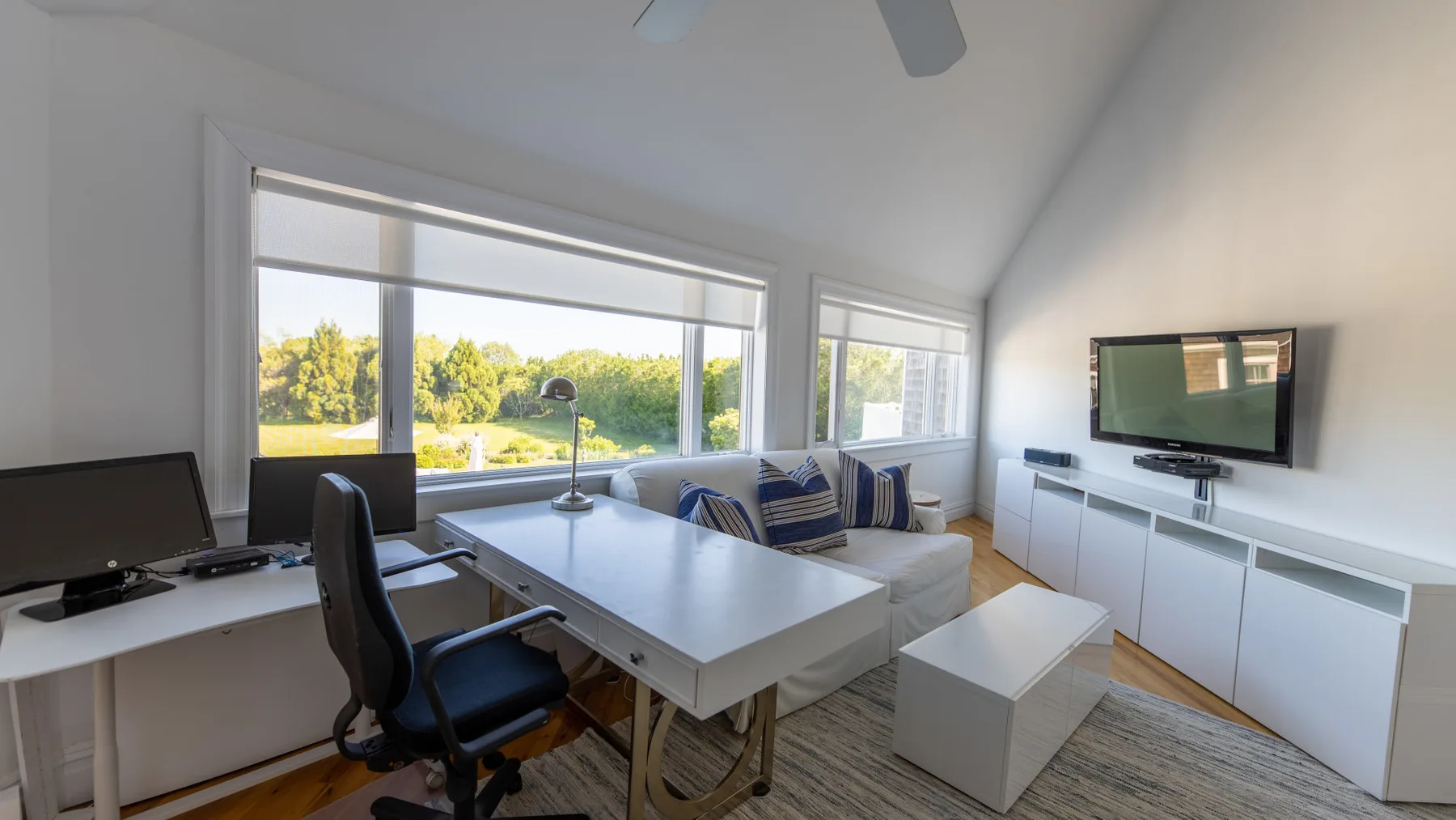 Una sala luminosa con mesa de comedor, escritorio y televisor.