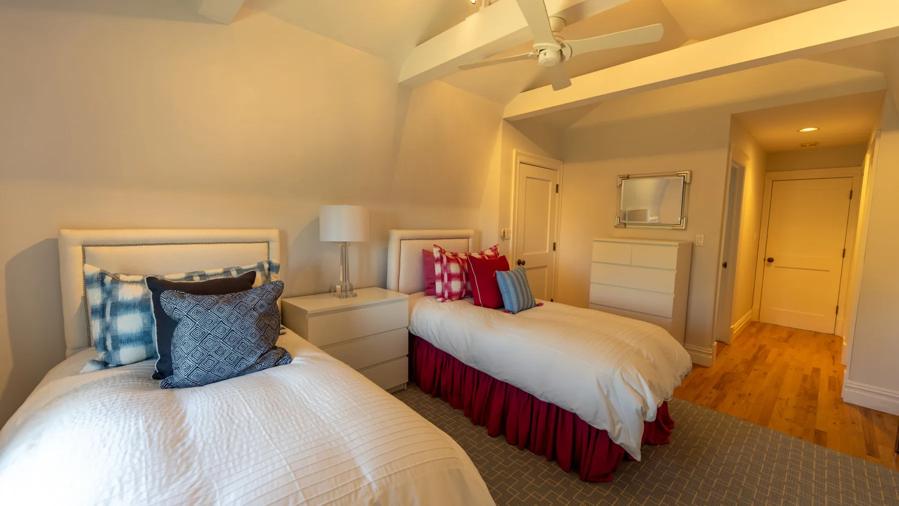 Un dormitorio con dos camas, una mesita de noche y un ventilador de techo.