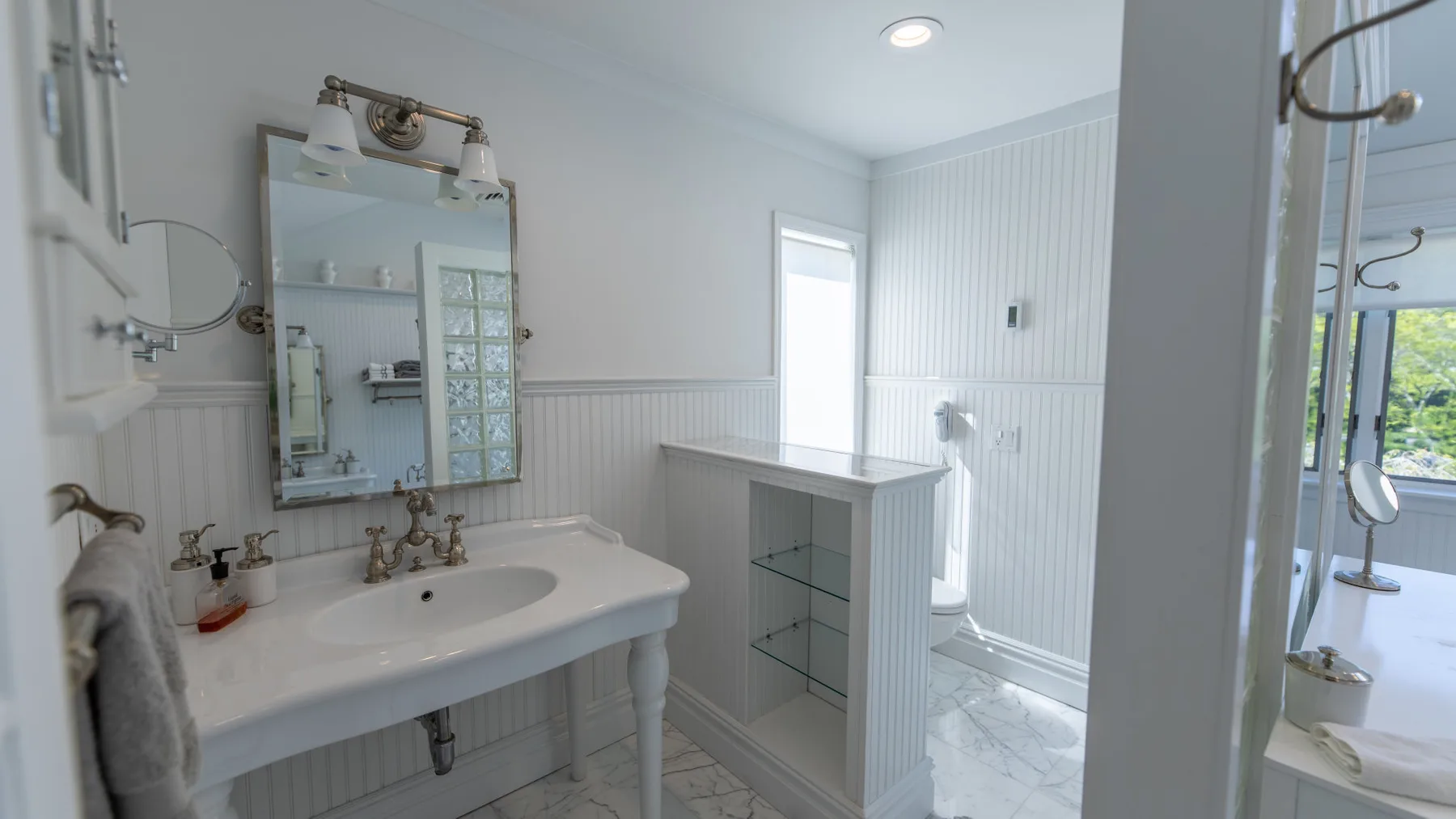Un baño luminoso con lavabo, espejo y ducha de vidrio.
