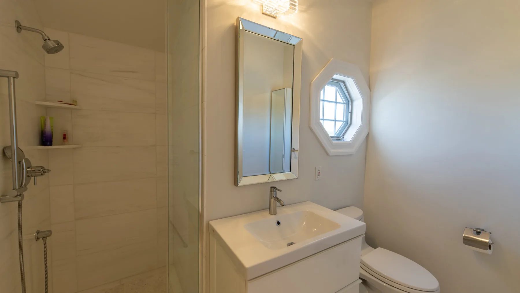Un baño con lavabo, espejo, ducha e inodoro.