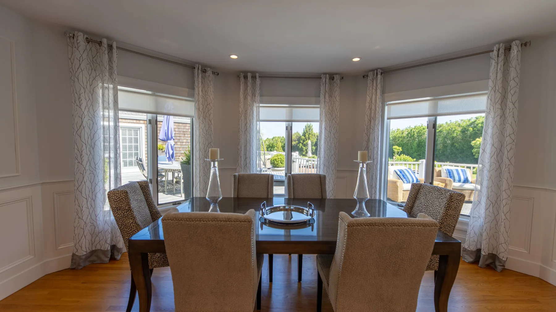 Un comedor con una mesa y sillas junto a grandes ventanas.