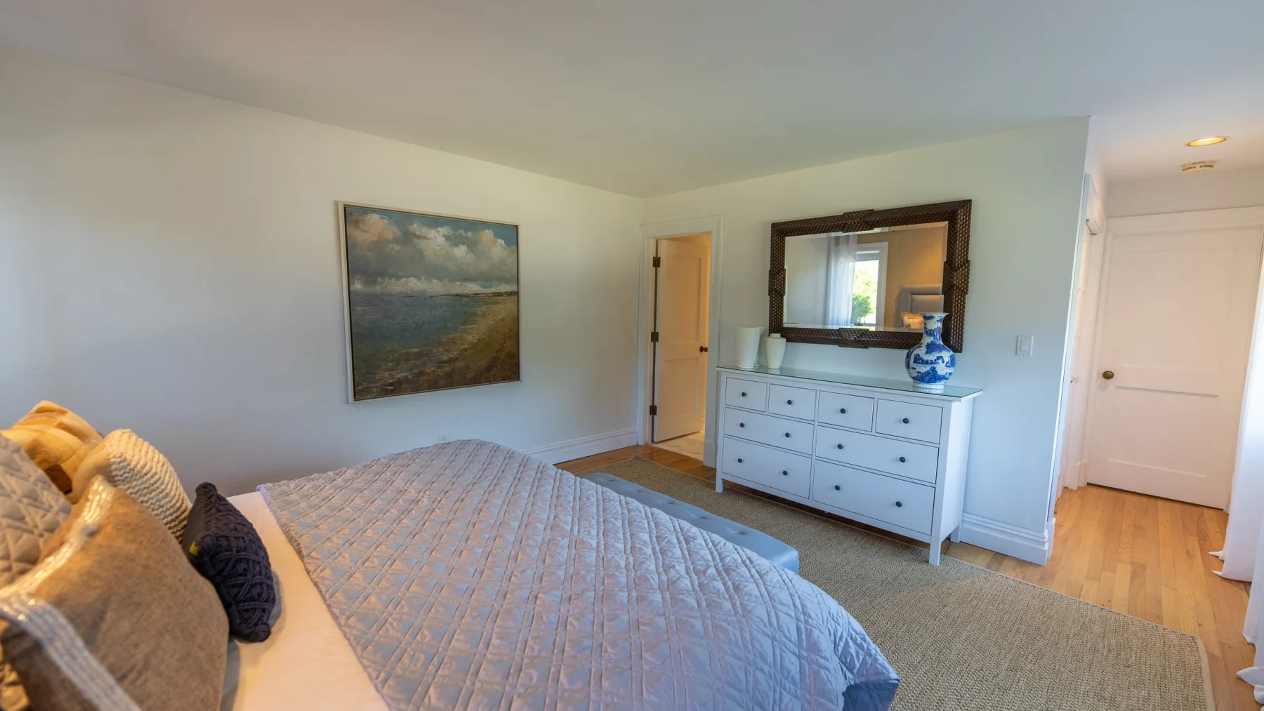 Un dormitorio con una cama, una cómoda y un cuadro de paisaje.