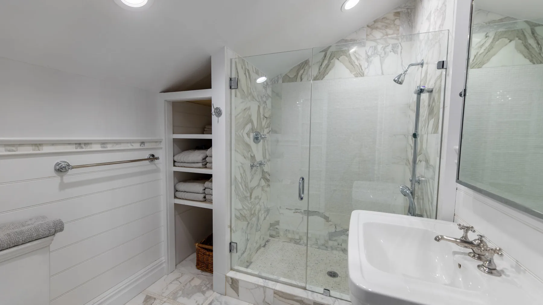 Un baño luminoso con una ducha de vidrio y un lavabo integrado.
