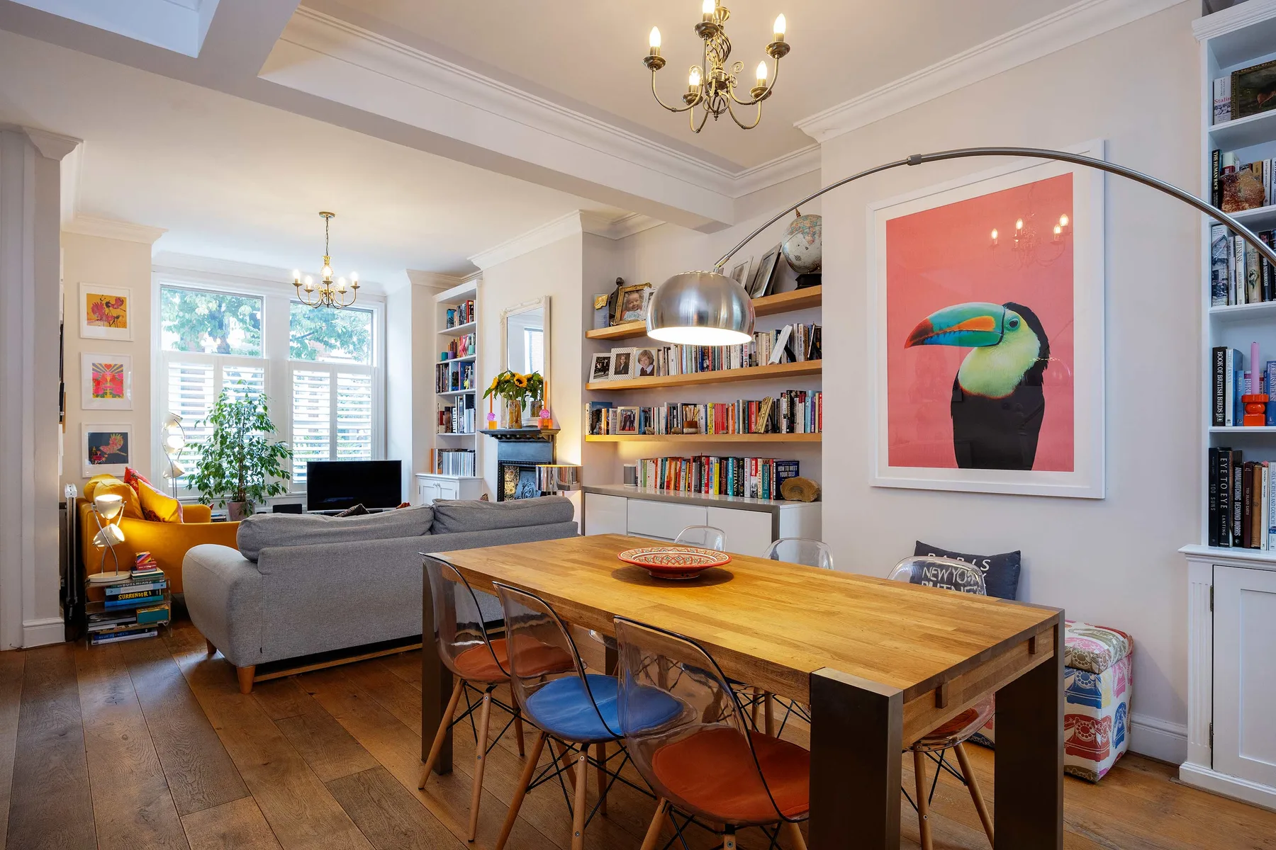 A bright living and dining room with a wooden table and bookshelves.