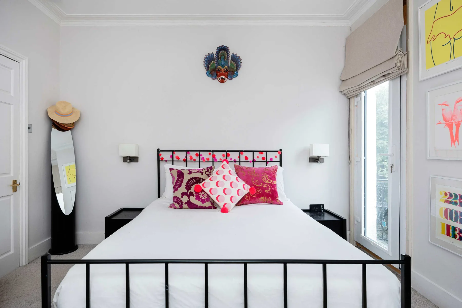 A bedroom with a neatly made bed and colorful pillows.