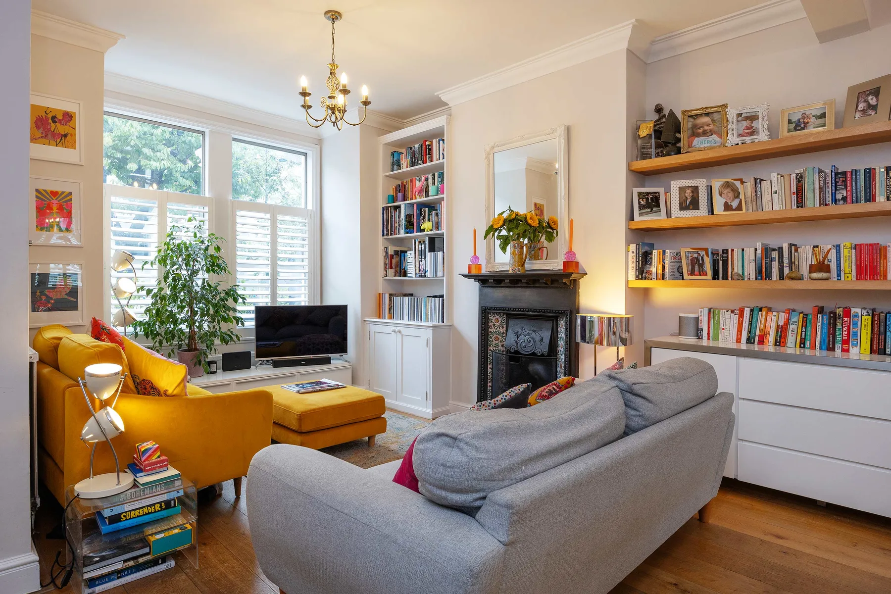 A bright living room with seating, bookshelves, and a fireplace.