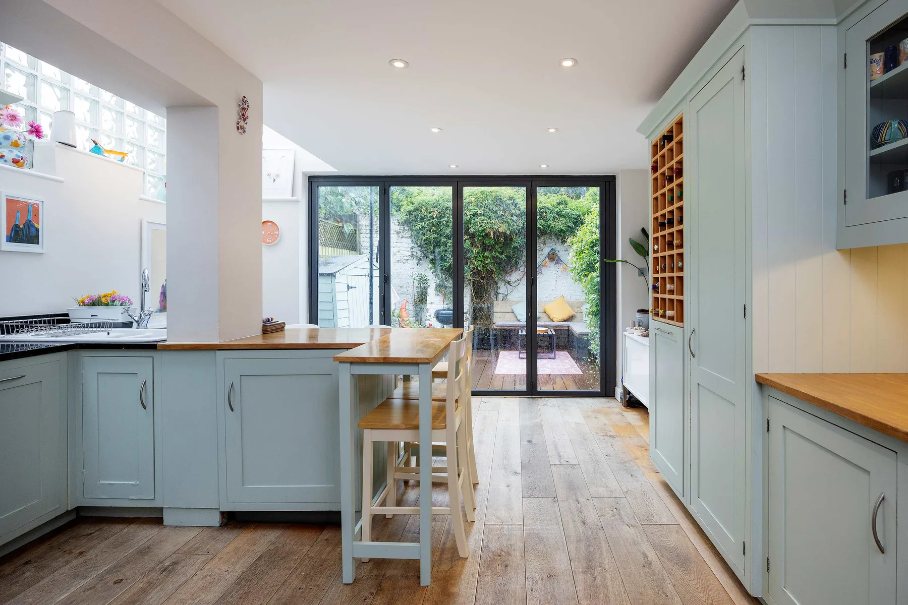 A bright kitchen with a central counter and glass doors opening onto a garden.