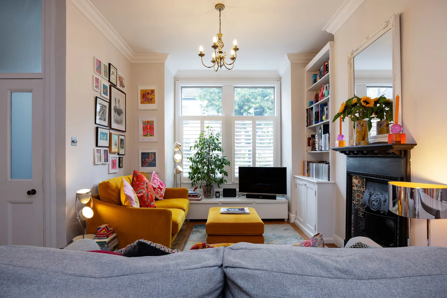 A bright living room with colorful seating, a television, and a fireplace.