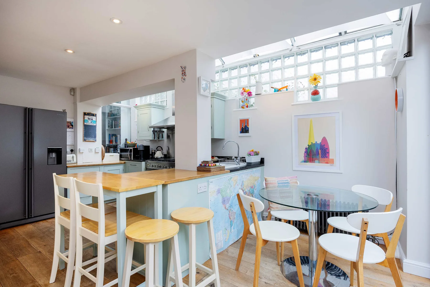 A bright kitchen and dining area with a wooden island and glass dining table.