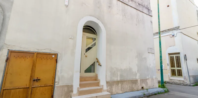 Una estrecha entrada arqueada da a una calle junto a una puerta amarilla.