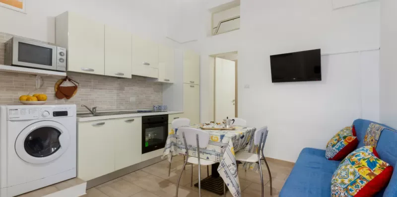 Una cocina y comedor luminosos con una mesa y asientos azules.