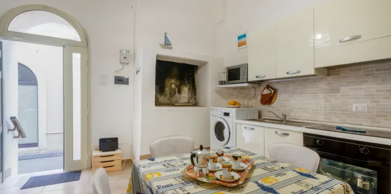 Una cocina con zona de comedor y una mesa puesta junto a los armarios.