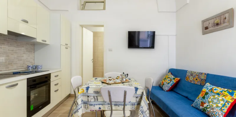 A dining area with a set table beside blue seating and a wall-mounted television.