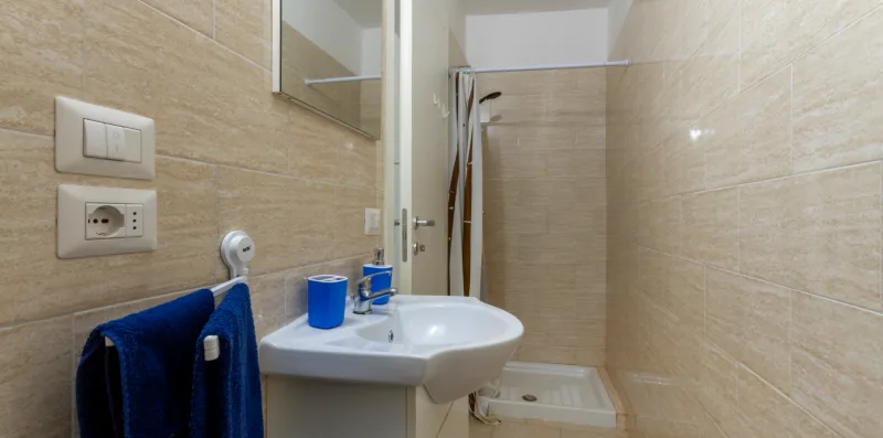 Un baño alicatado con lavabo, espejo de pared y zona de ducha.