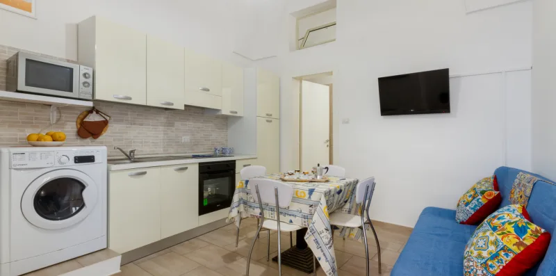 Una luminosa cocina y sala de estar con mesa de comedor y asientos azules.