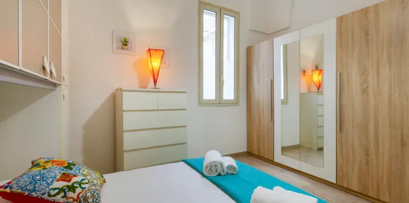 Un dormitorio con cama, cómoda y armario con espejo.