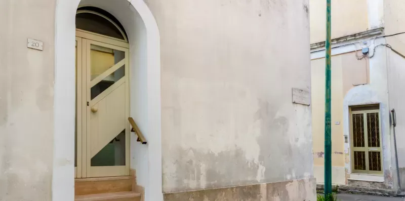 Un pasaje exterior con una puerta arqueada y una ventana cercana.