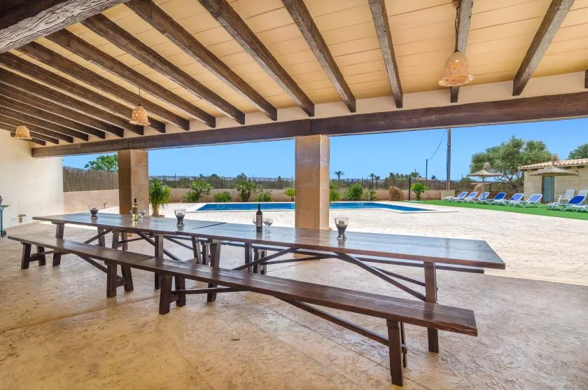 A covered outdoor dining area overlooks a swimming pool and open terrace.