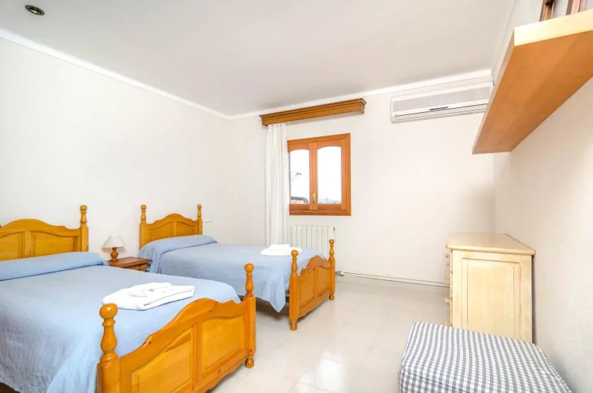 A bright bedroom with two wooden beds and a window.