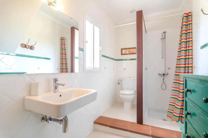 A bright bathroom with a sink, toilet, and shower.