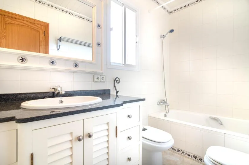 A bright bathroom with a bathtub, toilet, and vanity.