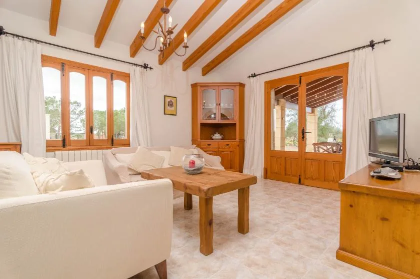 A bright living room with cream seating, a wooden coffee table, and doors opening to a patio.