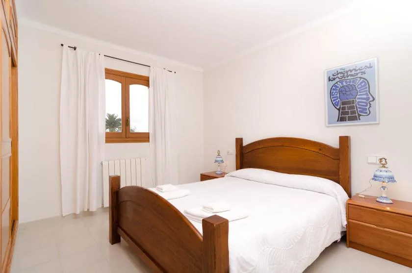 A bright bedroom with a wooden bed and white bedding.