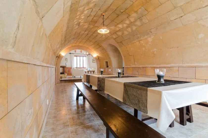 A long dining room with a vaulted stone ceiling and tables set along one side.