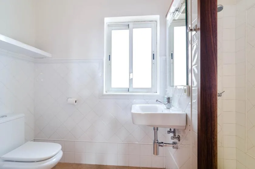 A bright bathroom with a window, sink, and toilet.