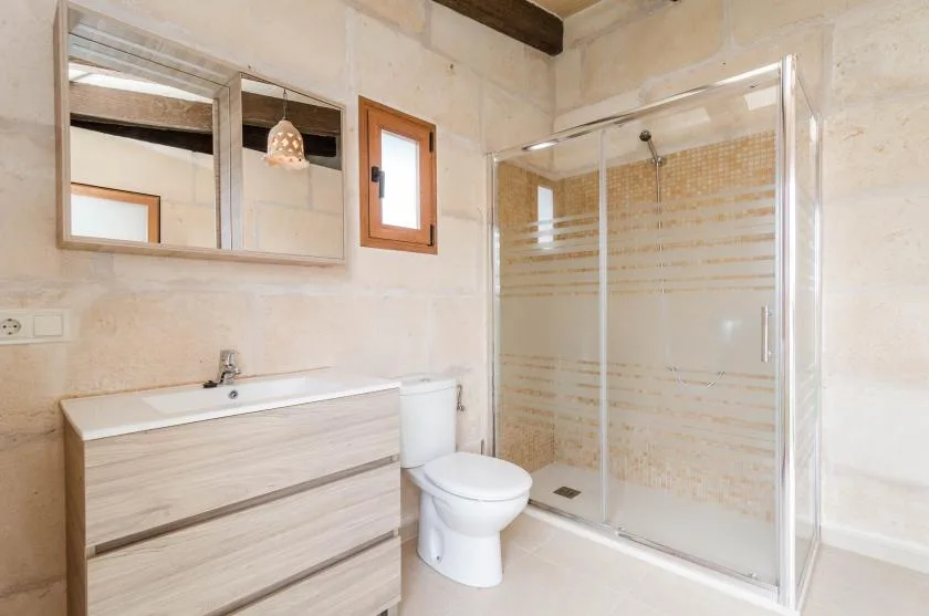 A bathroom with a vanity, toilet, and glass-enclosed shower.