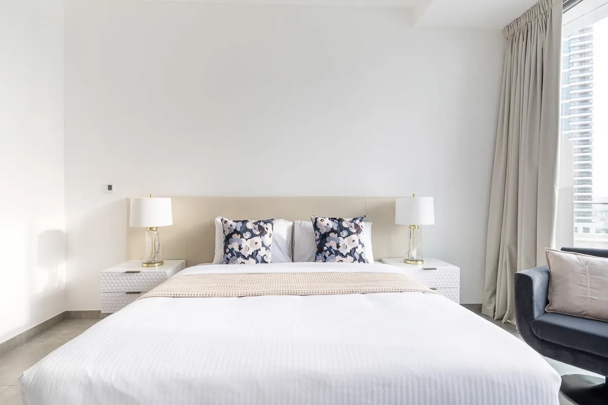 Un dormitorio luminoso con una cama bien hecha y lámparas de mesilla a juego.