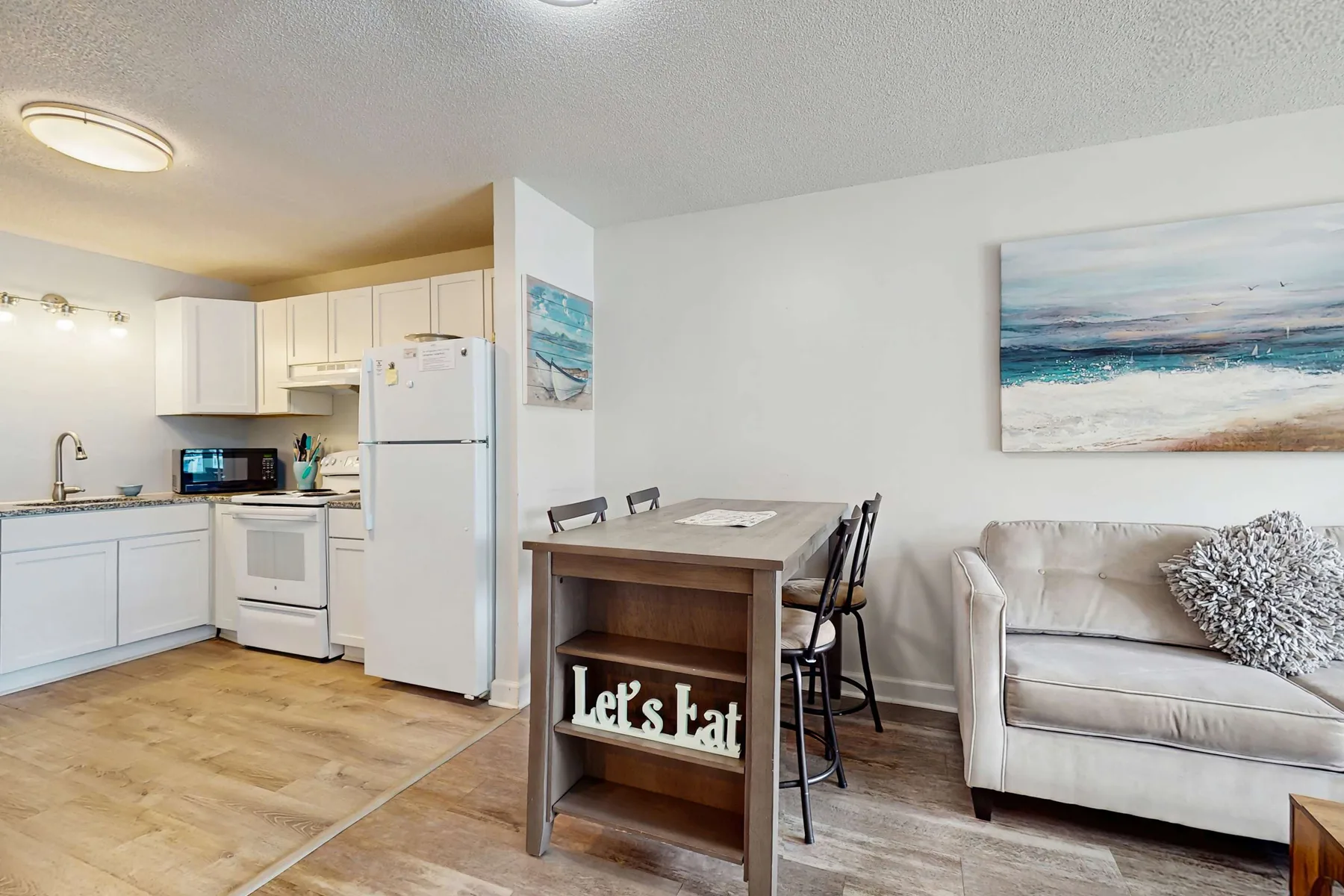 An open-plan kitchen and living area with a dining table and sofa.