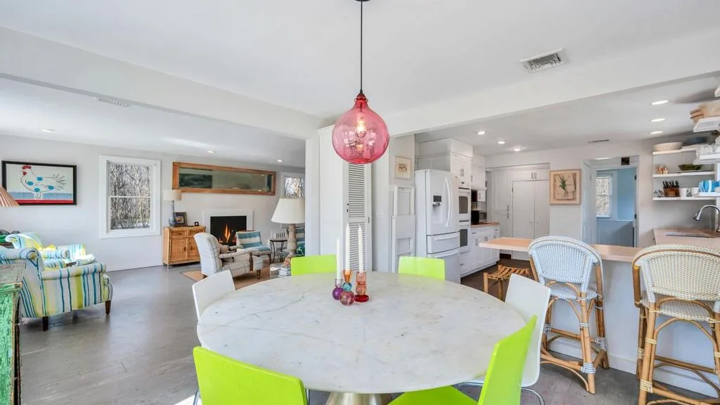 Una cocina y comedor de concepto abierto con una mesa redonda y una lámpara colgante colorida.