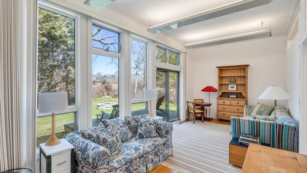 Una sala luminosa con asientos estampados y grandes ventanas con vistas al jardín.