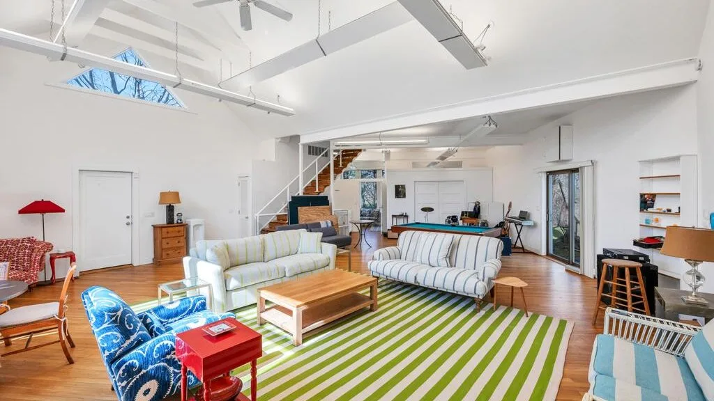 Una sala luminosa con asientos alrededor de una mesa de centro y una alfombra a rayas.