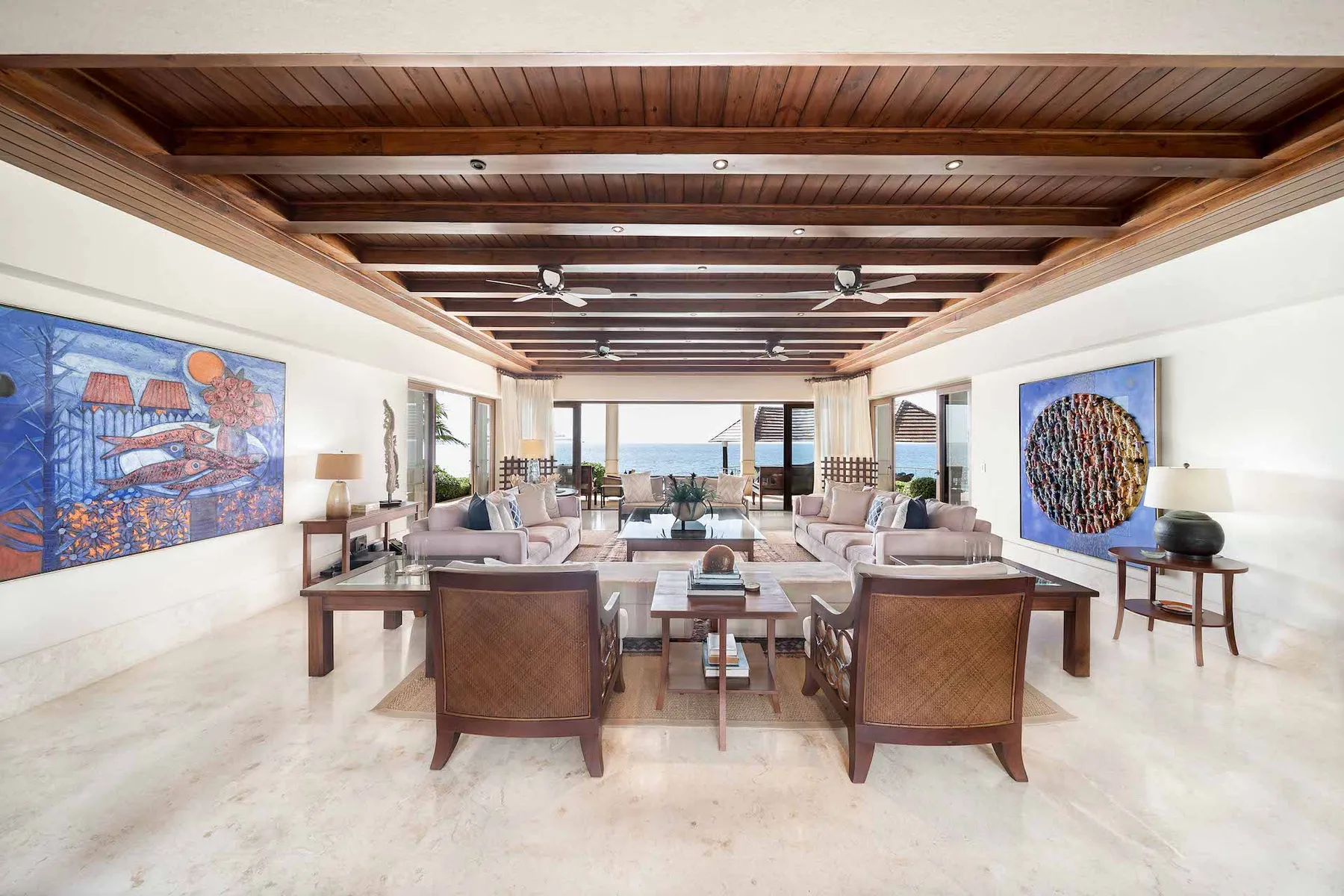 A spacious living room with seating arranged around a low table and ocean views beyond.