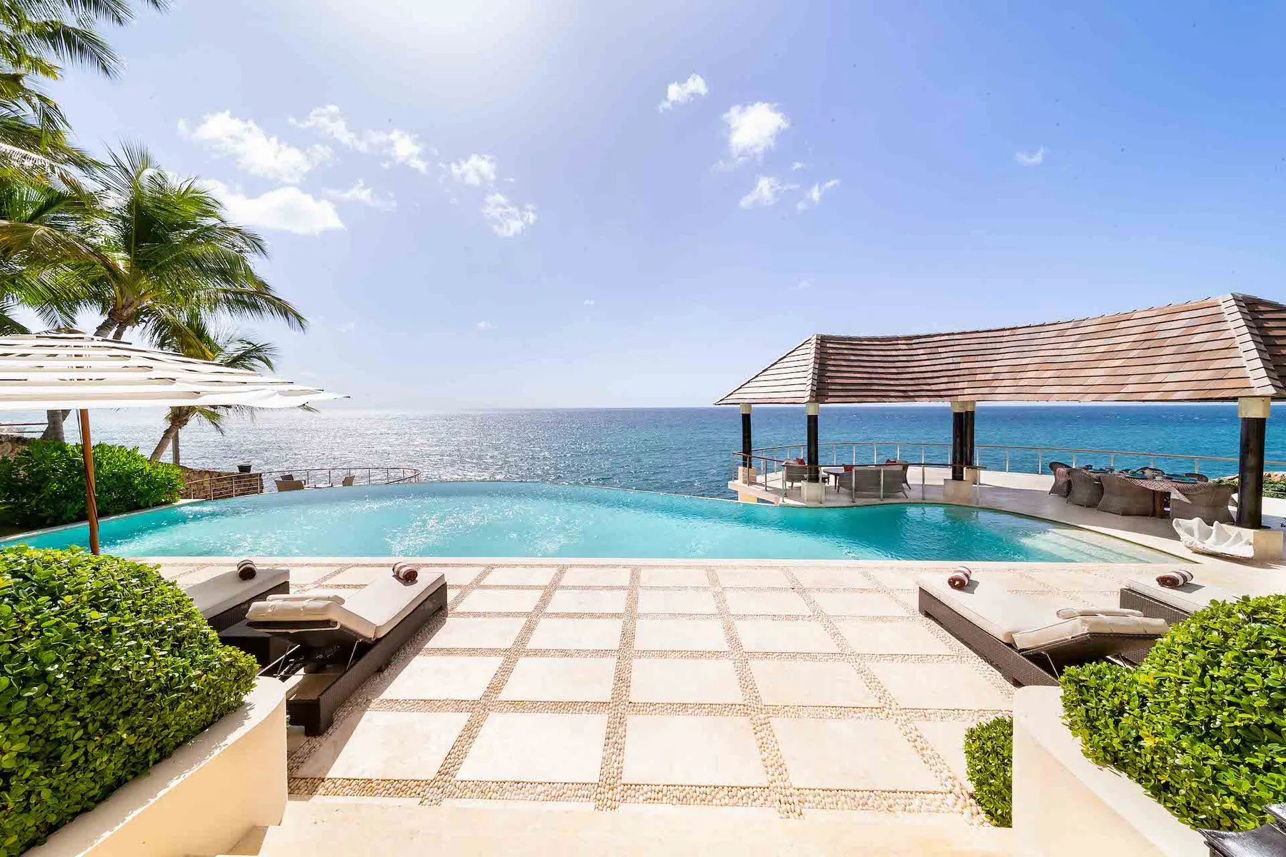 An outdoor pool and tiled terrace overlook the ocean.