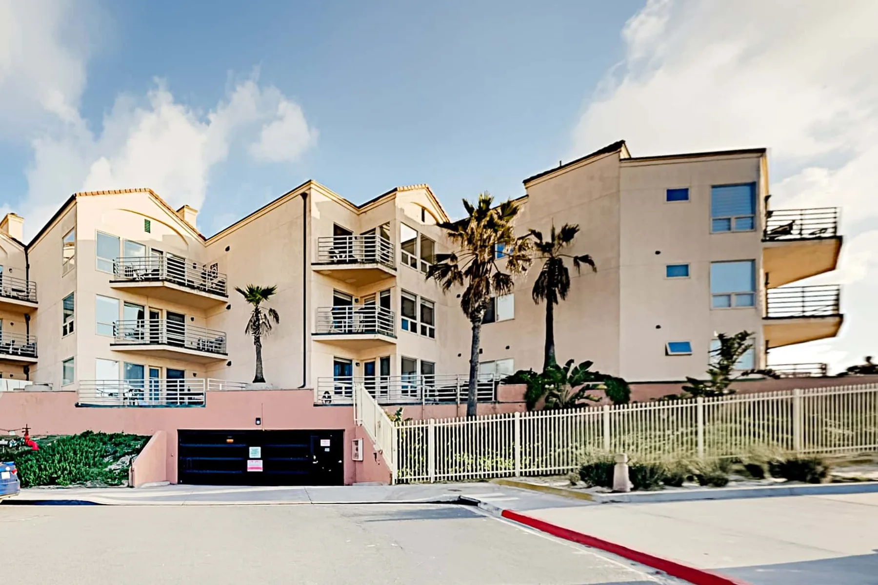 Edificios residenciales modernos de varios pisos se alzan detrás de una fachada vallada junto a la calle.