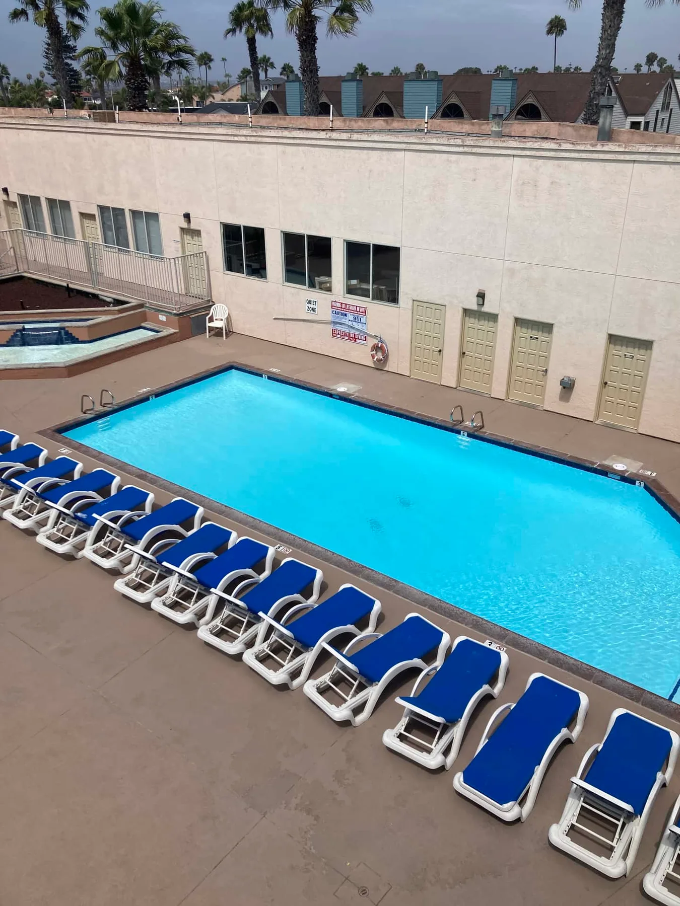 Una piscina al aire libre está rodeada de tumbonas azules.