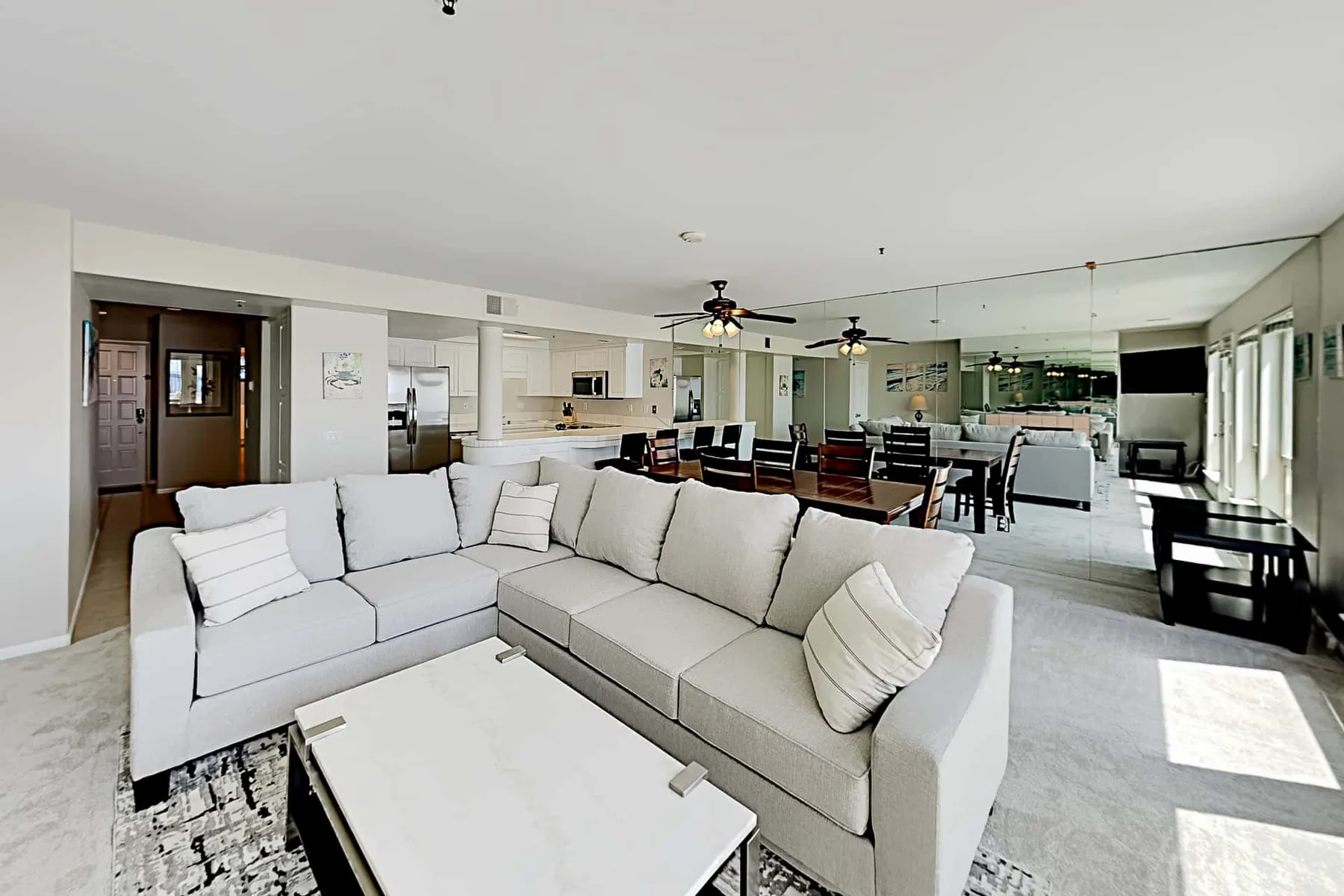 A bright living room with a sectional seating area and an open kitchen and dining space.